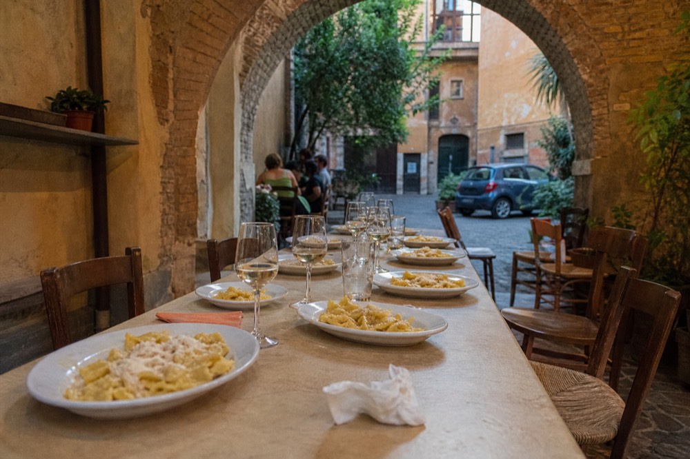 A cooking school dining table set with plates of fresh pasta and glasses of wine