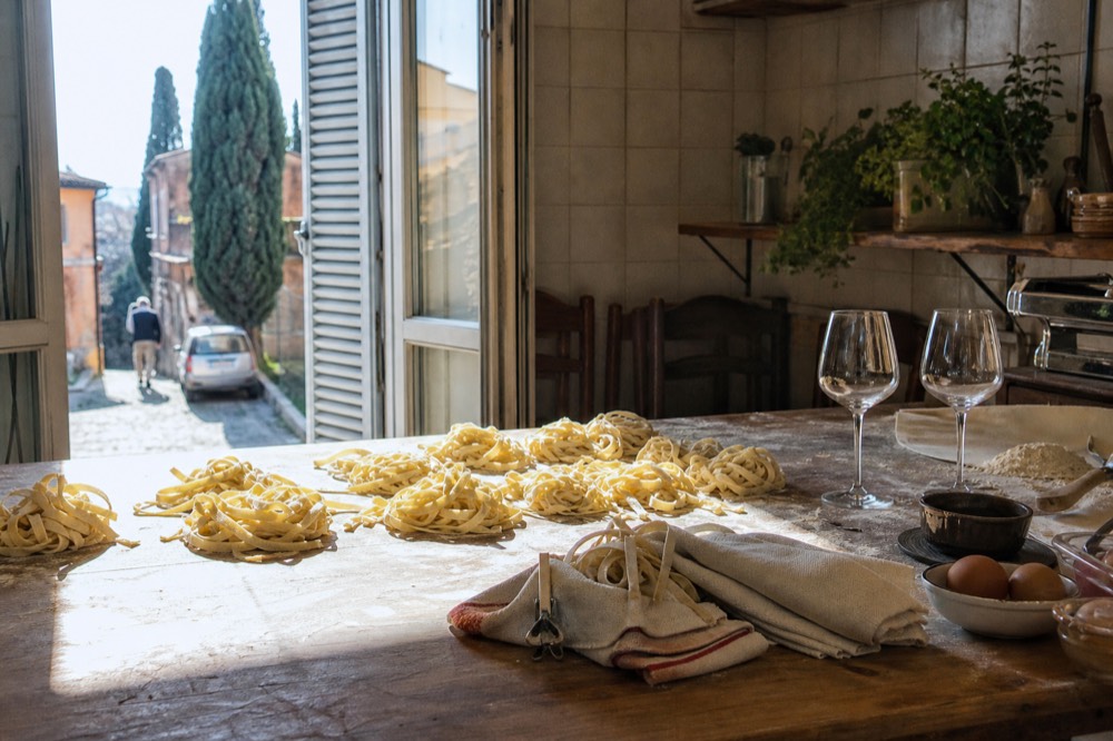 A table set with wine glasses, fresh pasta and a chalkboard menu