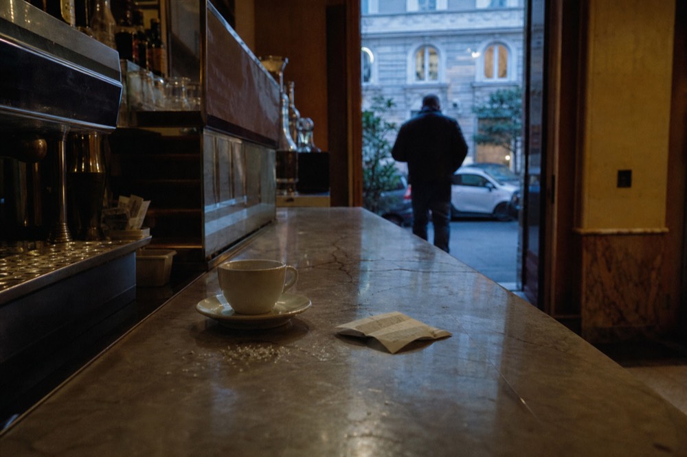 A receipt and an espresso cup on the marble counter of a Roman bar