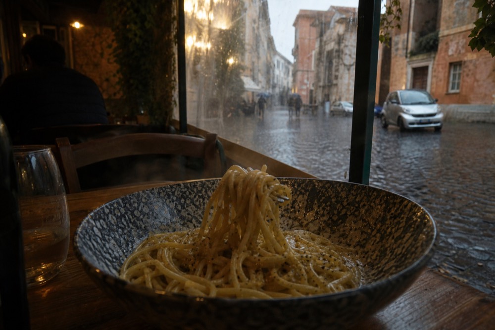 A close-up of spaghetti cacio e pepe being twirled with a fork in a ceramic bowl