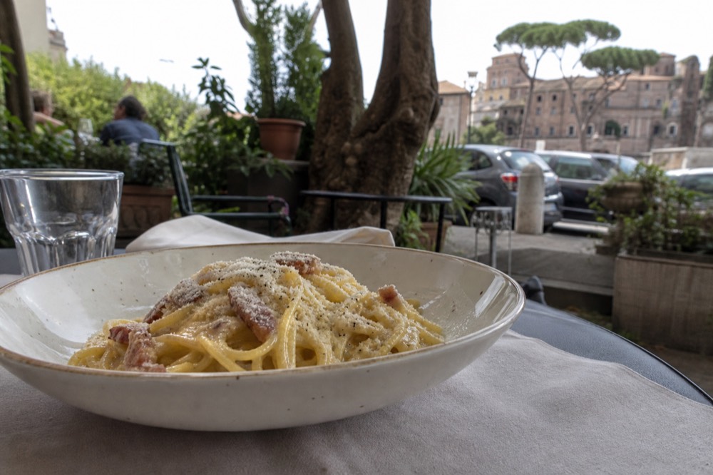 Fresh spaghetti with egg yolk sauce and guaciale pieces served in a shallow ceramic bowl