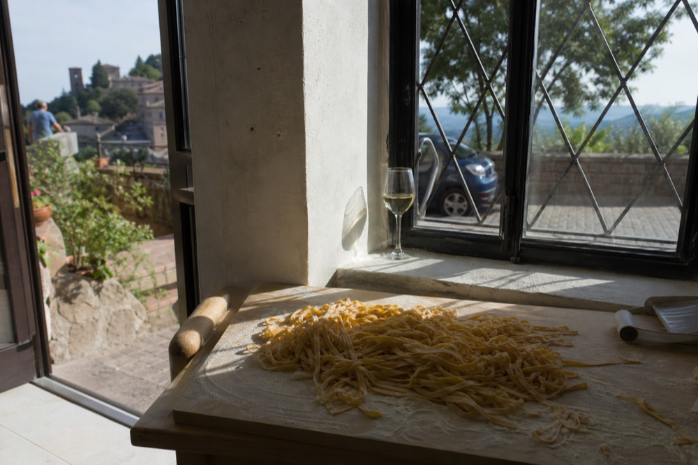 Long ribbons of fresh tagliatelle pasta piled on a wooden board in a pasta workshop