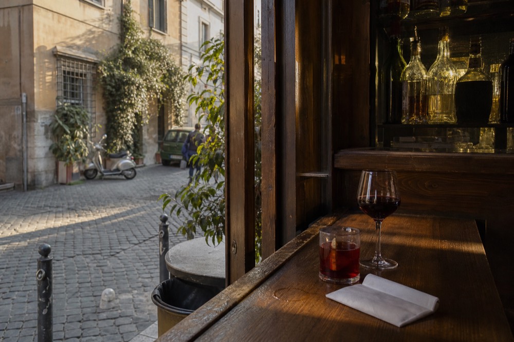 Glass of red wine and a bitter aperitif on a wooden bar top