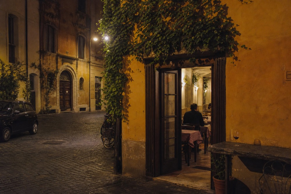 Lit trattoria doorway on an evening street in Rome