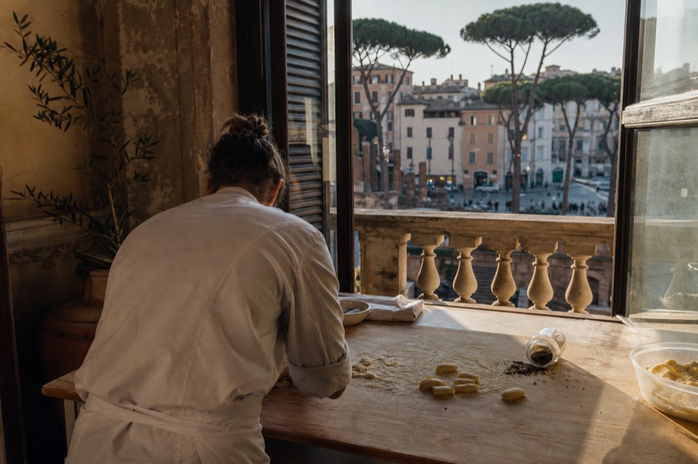 A cooking instructor demonstrating pasta shapes at a wooden counter in a Rome cooking school