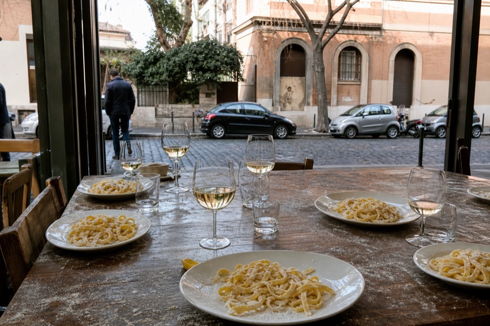 A table set with wine glasses and fresh pasta plates ready for a cooking class meal in Rome