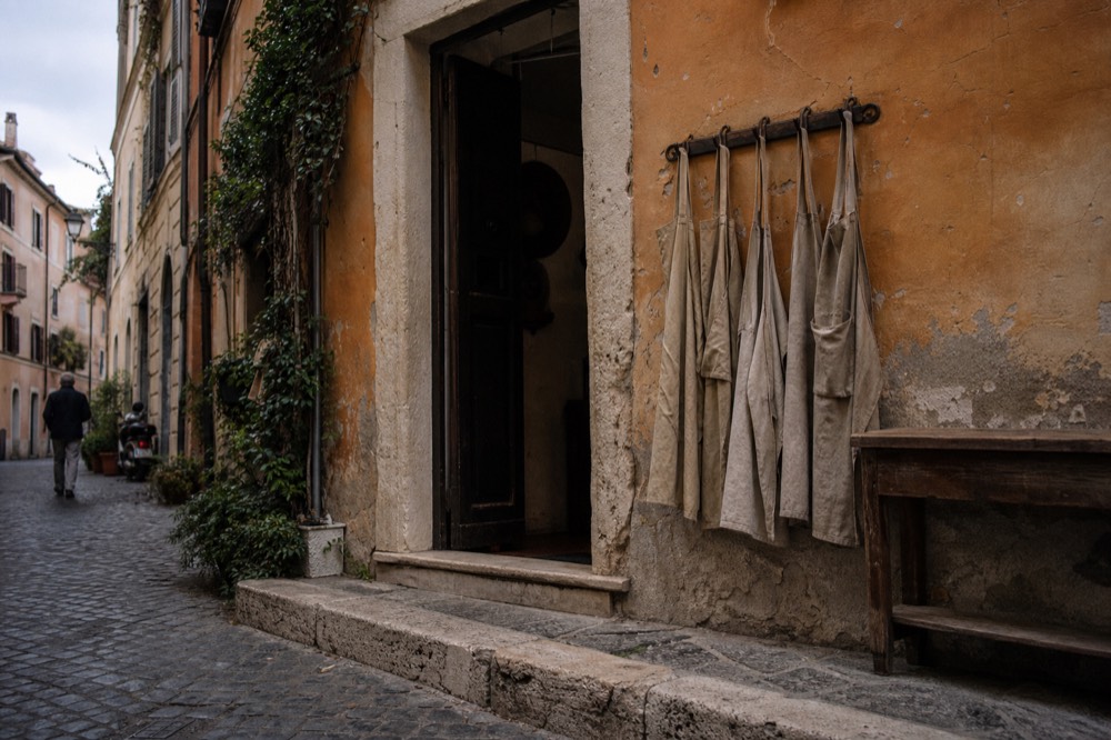 A Rome cooking school doorway with aprons hanging on hooks beside a wooden table