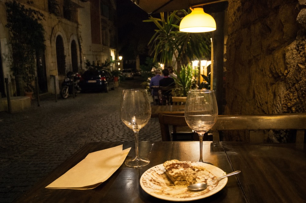 A restaurant bill with wine glasses and a finished dessert plate on a table at night