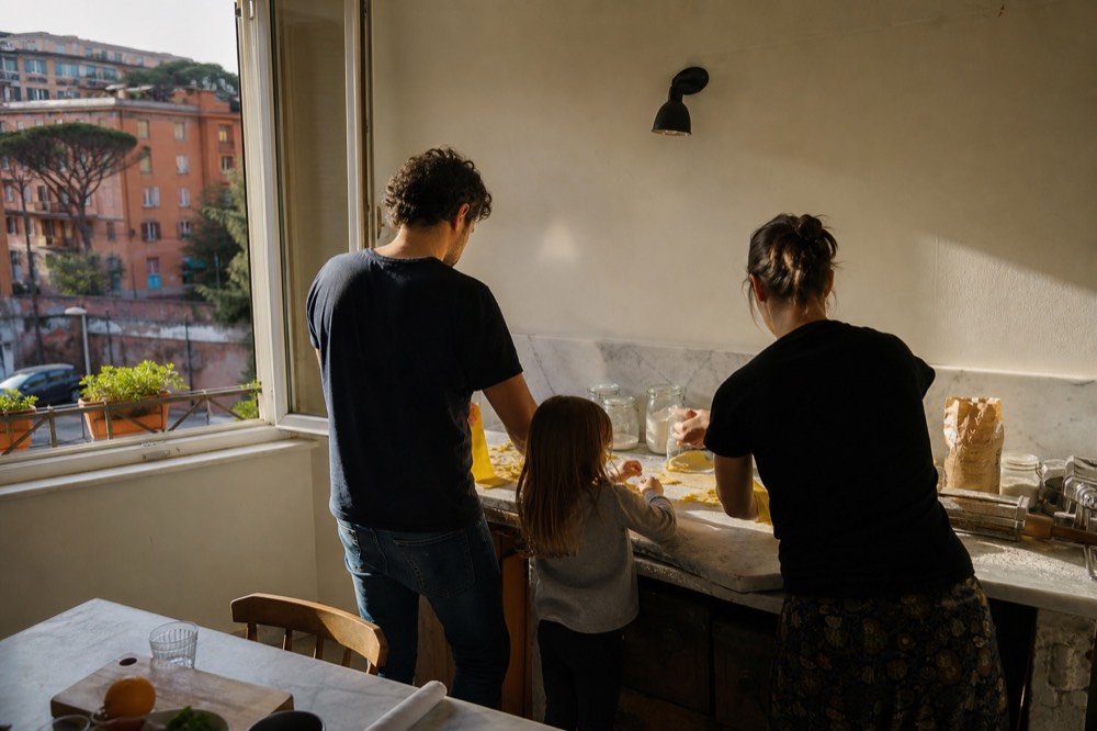 Couple and child laughing while folding fresh pasta dough together