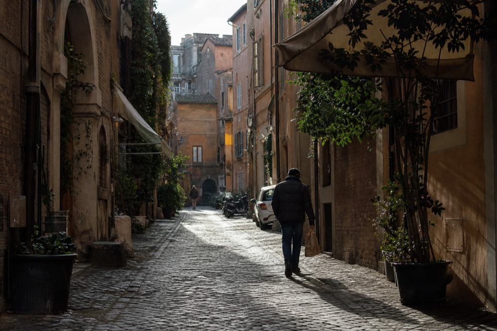 A narrow cobblestone lane with old brick buildings and hanging shop signs