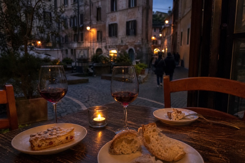 A table with wine glasses, bread and small plates in a candlelit Roman restaurant