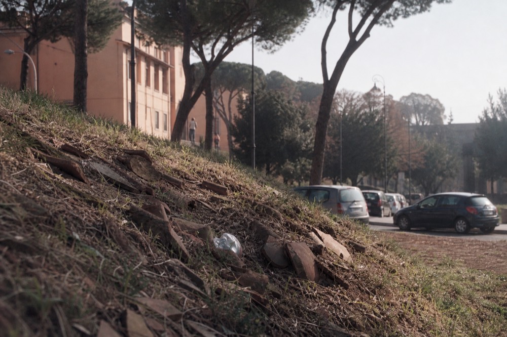 Grass-covered hill with fragments of ancient terracotta pottery exposed
